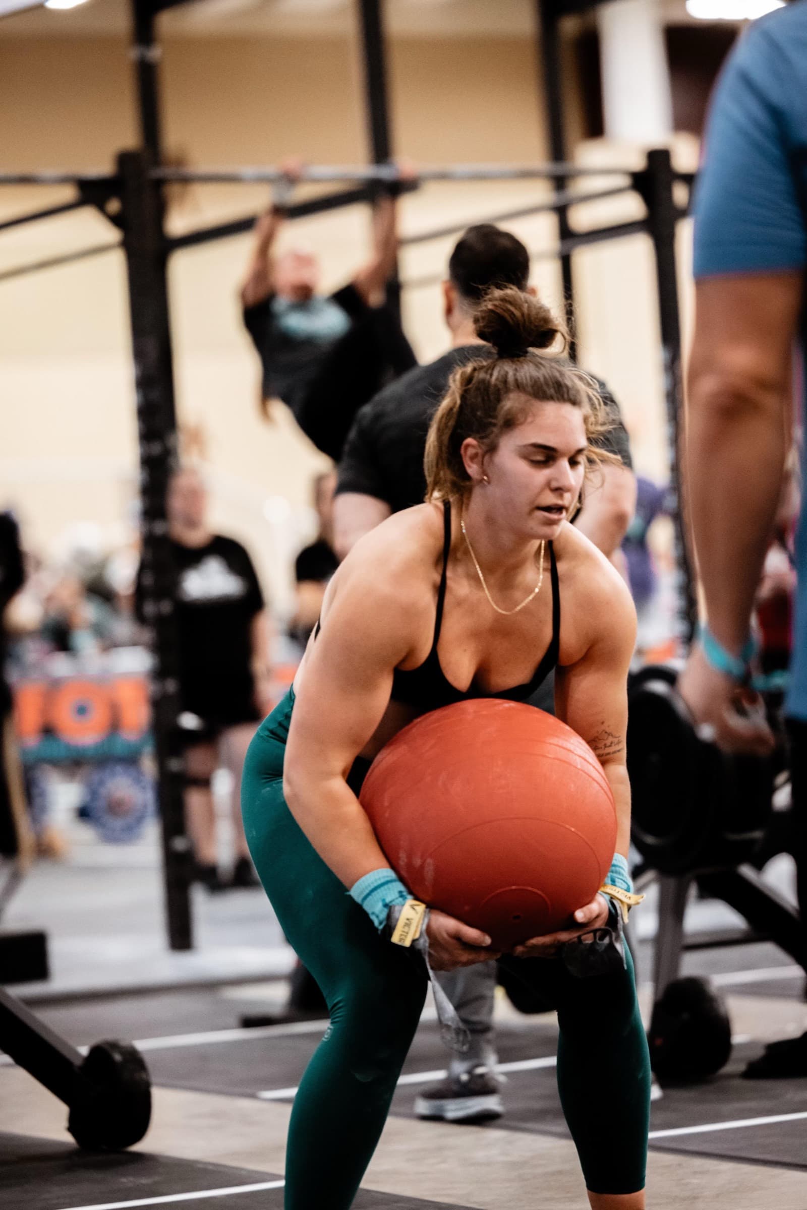 The coach carrying a heavy medicine ball through a competition workout