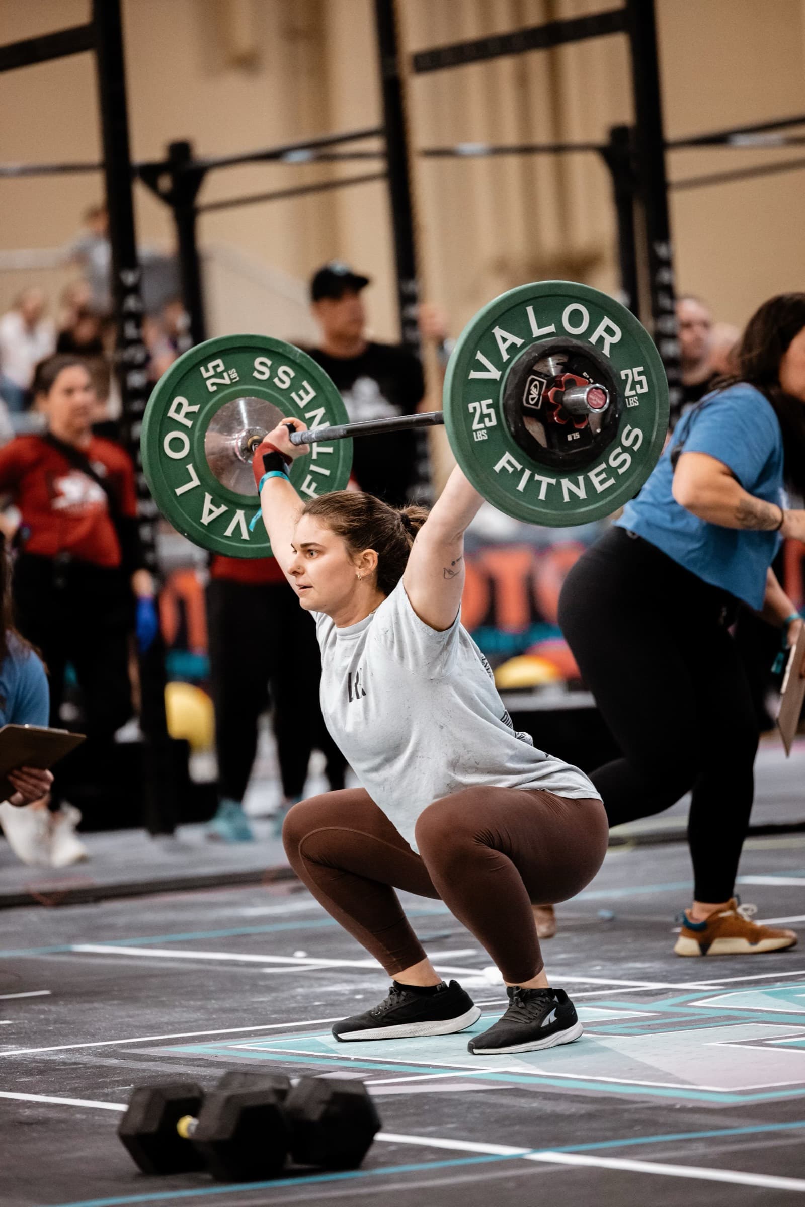 The coach catching a barbell overhead in a squat during a competition